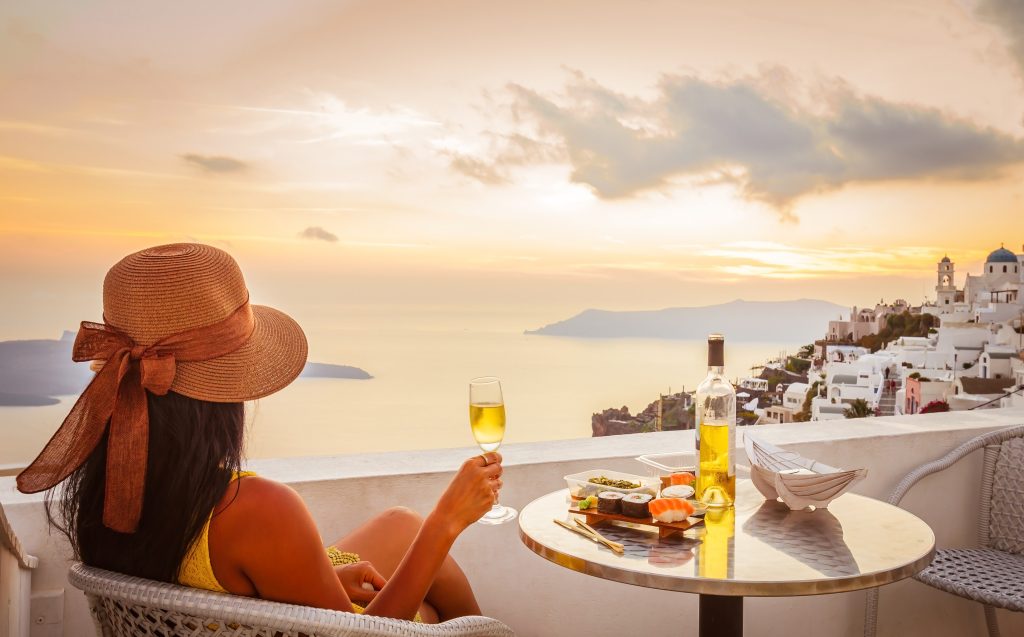 Female tourist enjoying food, wine and sunset view at Santorini, Greece - Accent On Travel