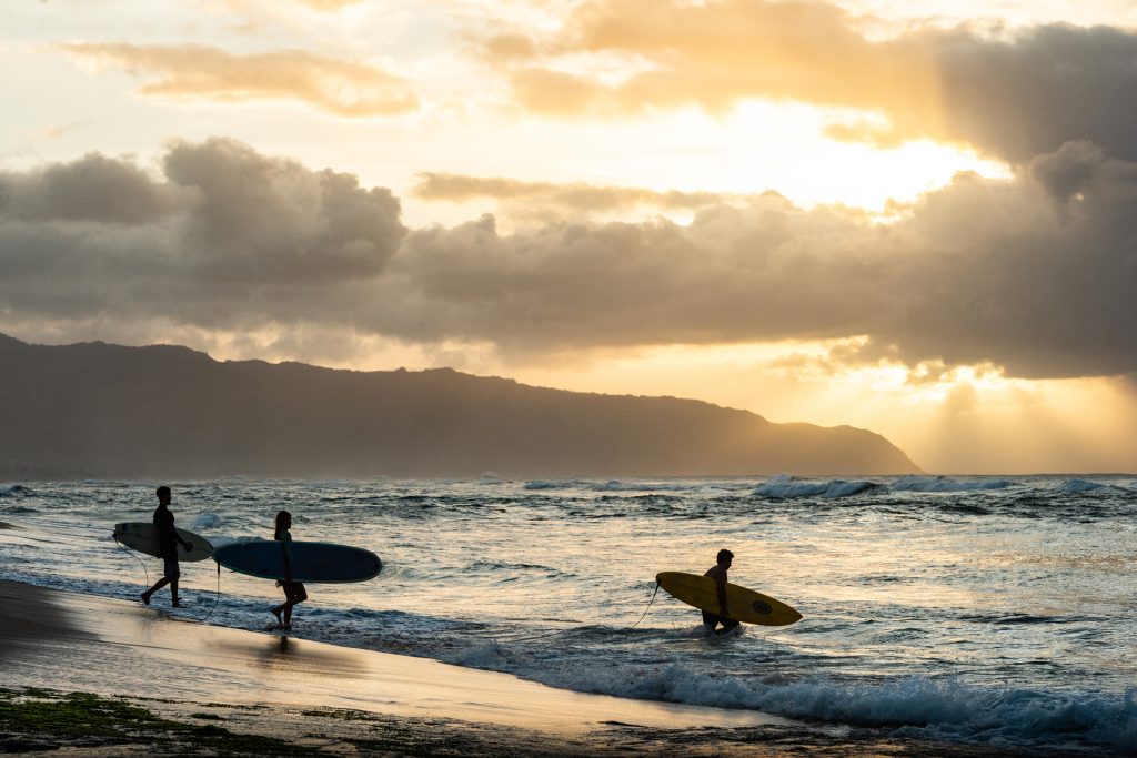 Three Surfers at Sunset at a North Shore Beach in Oahu Hawaii