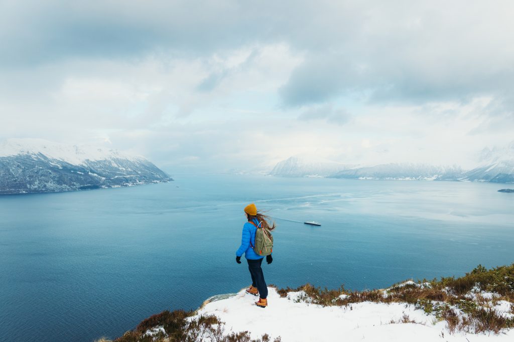 Woman with Backpack Hiking in Mountains Contemplating View of Winter - Accent on Travel